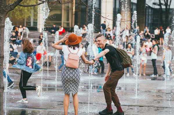 Moscú, Rusia - 1 de mayo de 2018. Gente activa en la ciudad. Joven hombre, mujer usar falda y otras personas que ordenan en una fuente de la ciudad — Foto de Stock
