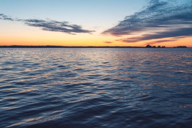 Akşam deniz batımı manzarası. Çerçevede deniz daha çok yer kaplar. Metnin için kopyalama alanı