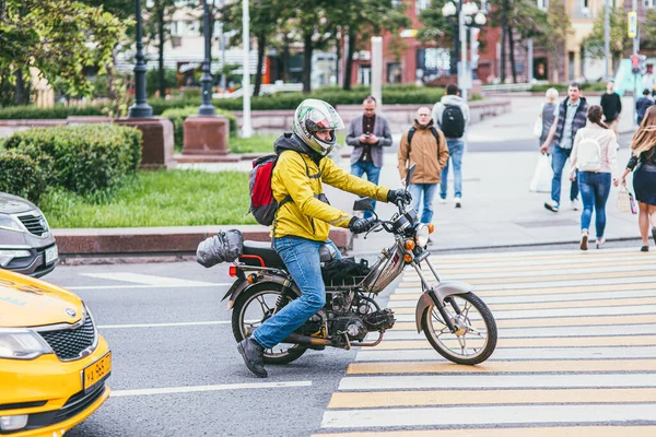 МОСКВА, Россия 7 июля 2017 года: молодой человек в шлеме и желтой куртке сидит на мотоцикле на пешеходном пешеходе и ждет зеленого света — стоковое фото