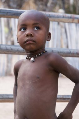 Epupa Falls, Namibya - 12 Ağustos 2011: Geleneksel kolye ayakta Kaokoland bölgedeki köyünde kimliği belirsiz çocukla. Namibya ülkesindeki en vahşi ve en az nüfuslu bölgelerinden birinde alandır