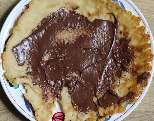 Pannkaka på tallrik med choklad pasta på trä bakgrund — Stockfoto