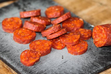 Taze yapılmış İspanyol domuz chorizo sosis kırmızı biber, sarımsak, biberiye ve biberiye ile yapılan, siyah bir kesme tahtası üzerinde dilimlenmiş