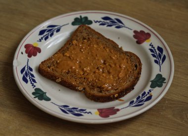 Ahşap arka planda beyaz tabaküzerinde fıstık ezmesi ile Ekmek