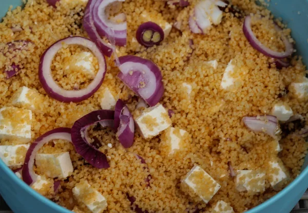 Schüssel mit Couscous-Salat serviert mit roten Zwiebeln, Feta-Käse und sonnengetrockneten Tomaten — Stockfoto