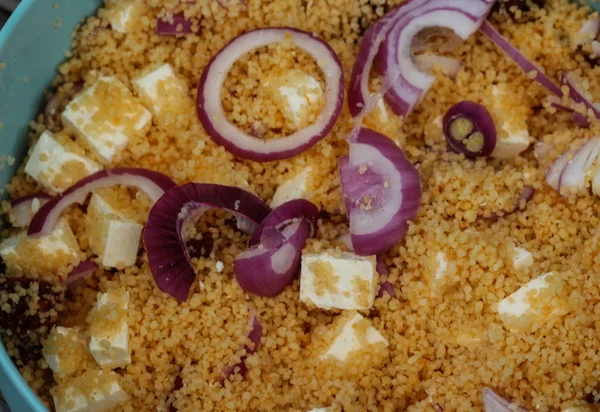 Schüssel mit Couscous-Salat serviert mit roten Zwiebeln, Feta-Käse und sonnengetrockneten Tomaten — Stockfoto