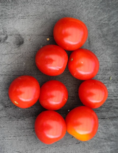 Tomate rojo cereza fresco sobre fondo de tabla de cortar negro — Foto de Stock