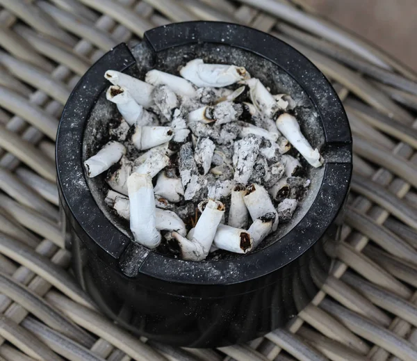 Filled ashtray with cigarettes and ash outside Stock Picture