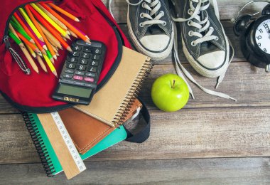 Tahta masada okul malzemeleriyle dolu sırt çantası.
