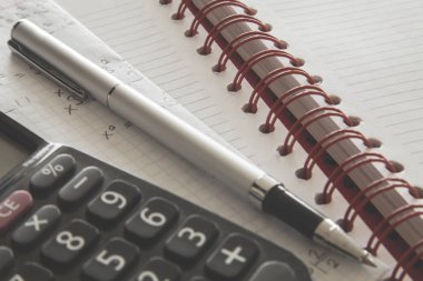 Hesap makinesi üstünde defter kalem ile