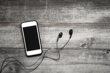 Ahşap arka plan üzerinde kulaklık ile cep telefonu