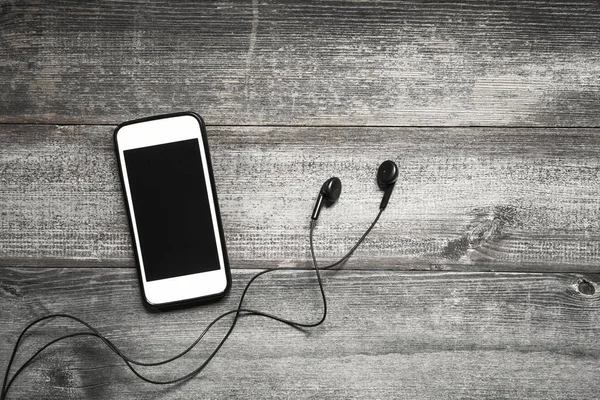 Ahşap arka plan üzerinde kulaklık ile cep telefonu