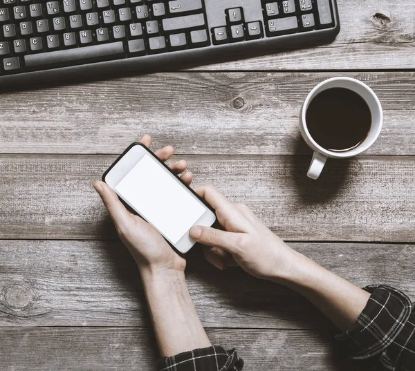 Genç kadın el cep telefonu üzerinde ahşap masa tutarak