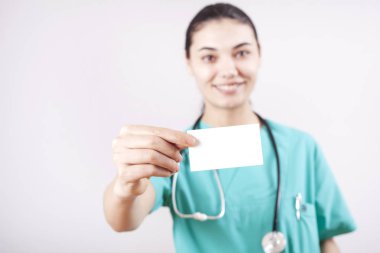 Genç kadın doktor el boş kartı gri arka plan üzerinde tutarak