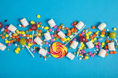 Renkli lolipoplar ve farklı renkte yuvarlak şekerler. Üst görünüm.