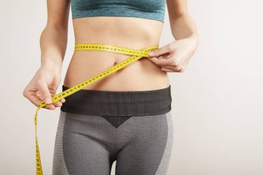 Gri arka planda ölçmek ile genç çekici kadın vücudu