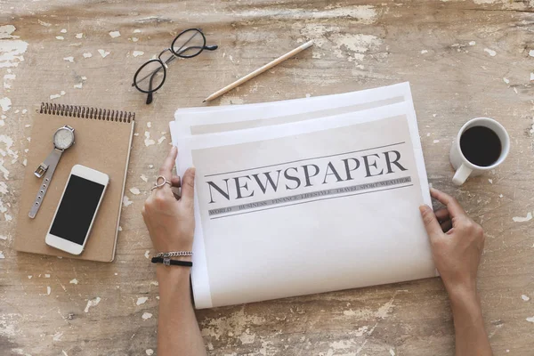 stock image Woman reading newspaper on wooden background