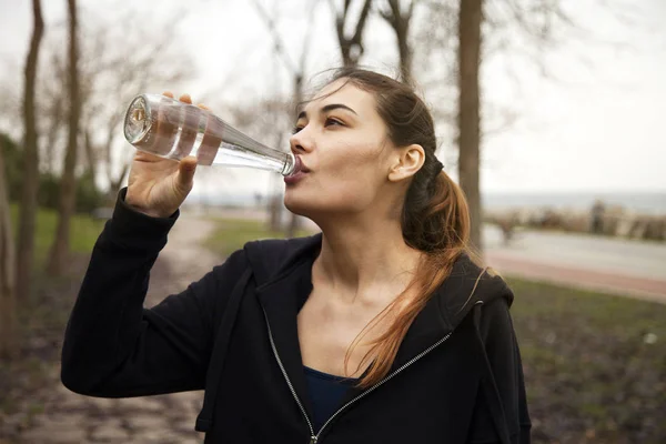 Young beautiful woman drink water in outdoors