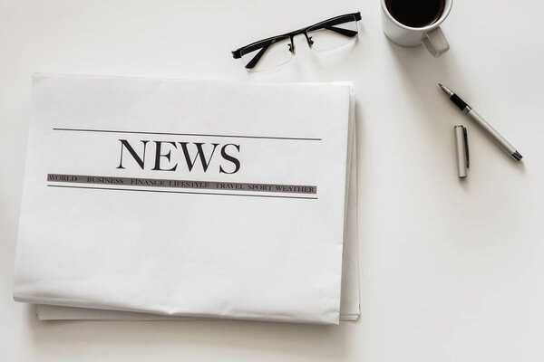 Newspaper and coffee on white background