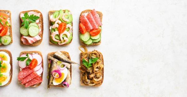 Set of different sandwiches with meat, vegetables, seafood. Assortment open sandwiches on light stone background with free text space. Tasty healthy snack. Top view, flat lay. — Stock Image Set Different Sandwiches Meat Vegetables Seafood Assortment Open Sandwiches Light Stock Photo