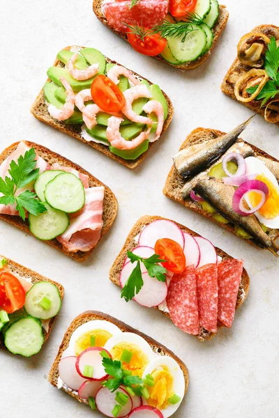 Set of different sandwiches with meat, vegetables, seafood. Assortment open sandwiches on light stone background. Tasty healthy snack. Top view, flat lay. — Stock Image Set Different Sandwiches Meat Vegetables Seafood Assortment Open Sandwiches Light Stock Photo