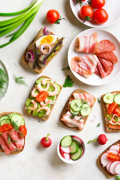 Different open sandwiches with meat, vegetables, seafood on light stone background. Tasty healthy snack. Top view, flat lay. — Stock Image Different Open Sandwiches Meat Vegetables Seafood Light Stone Background Tasty Stock Photo