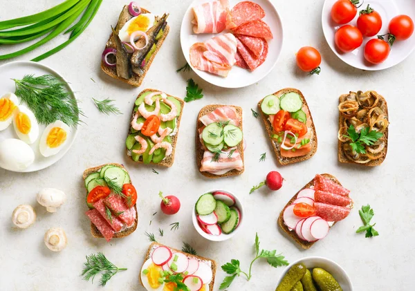 Set of different sandwiches with meat, vegetables, seafood. Assortment open sandwiches on light stone background. Tasty healthy snack. Top view, flat lay. — Stock Image Set Different Sandwiches Meat Vegetables Seafood Assortment Open Sandwiches Light Royalty Free Stock Images