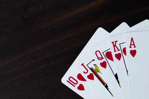 playing cards on black background. royal flush in hearts