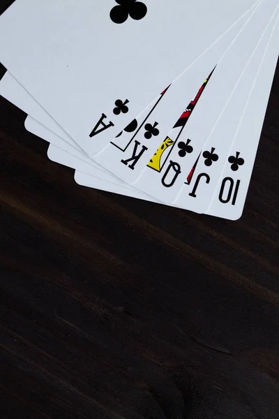 playing cards on black background. royal flush in clubs