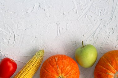 görmek için beyaz masada taze meyve ve sebze. Kabak, kırmızı domates, sarı mısır, yeşil elma ve salatalık ve biber beyaz arka plan üst görünümü.