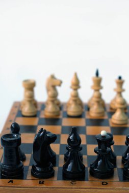 bir satranç tahtası üzerinde beyaz ve siyah satranç taşları. oyunun başlangıcı. Beyaz piyon ilk hamleyi yaptı. satranç tahtasının bir parçası