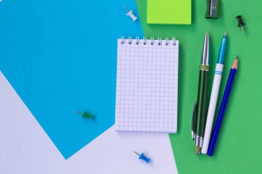 beyaz, mavi ve yeşil arka plan üst görünümünde izole defter ve kalem