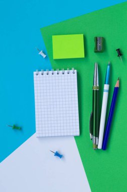 beyaz, mavi ve yeşil arka plan üst görünümünde izole defter ve kalem