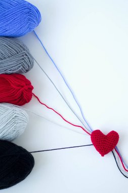 iplik renkli skeins ve beyaz bir arka plan üzerinde kırmızı örme kalp