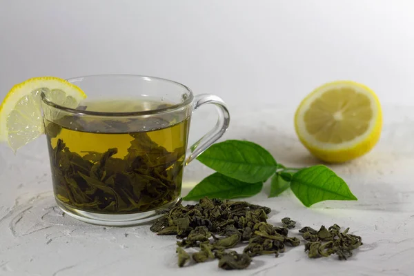 green tea with lemon and leaves on white background