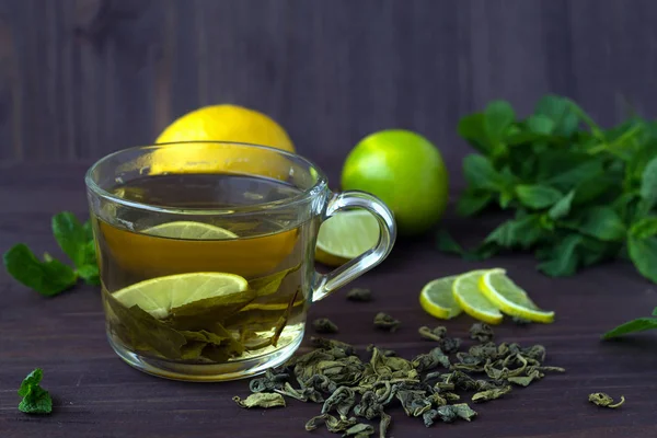 healthy lifestyle. cup of green tea with lemon and fresh mint on wooden background