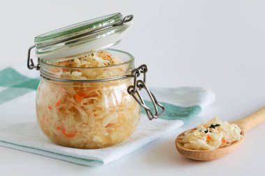Vejetaryen yemeği. Beyaz arka planda cam bir tabakta turuncu havuçlu ev yapımı lahana turşusu. Konserve yiyecek kavramı. Boşluğu kopyala