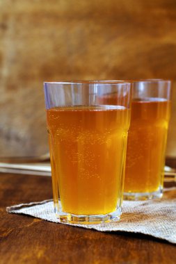 Kahverengi arka planda ev yapımı ekmek. Yaz meşrubatı. Tahta bir masanın üzerinde çuval bezli bir bardak bira. dikey