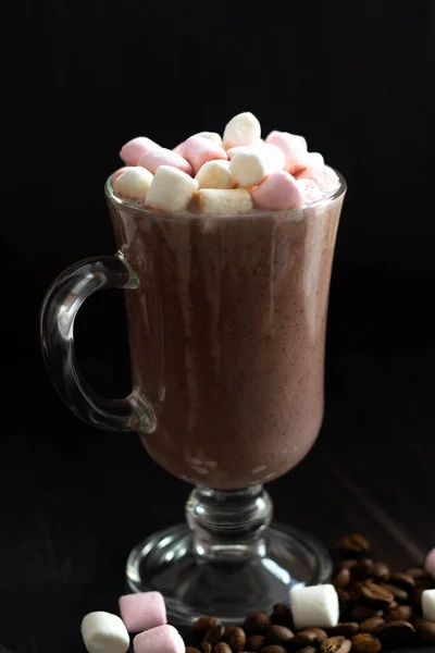 cup of coffee with marshmallows. glass of cappuccino with cream on a dark table. hot chocolate on a wooden background. hot drinks winter and autumn. vertical. copy space.