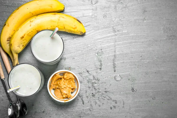 Muz ve fıstık ezmesi ile protein güler yüzlü. Rustik arka plan üzerinde.