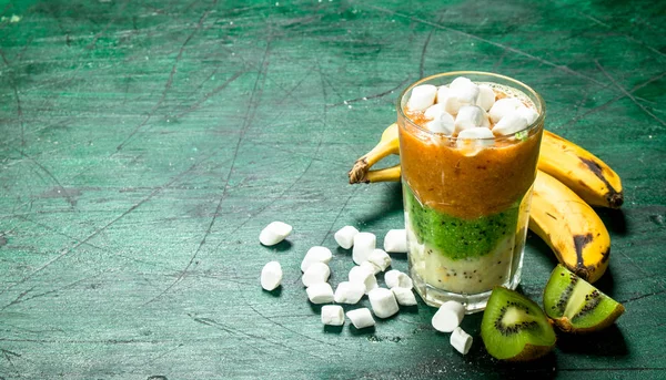Fruit smoothie with marshmallows. On rustic background.