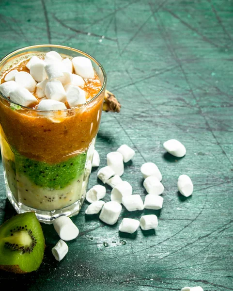 Fruit smoothie with marshmallows. On rustic background.