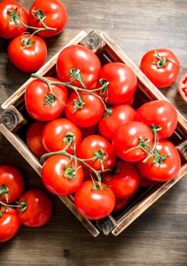 Bir kutu içinde taze domates. Ahşap bir masaya.