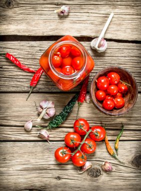 Bir bardak turşu domates sarımsak ve otlar ile jar. Ahşap bir arka plan üzerinde.