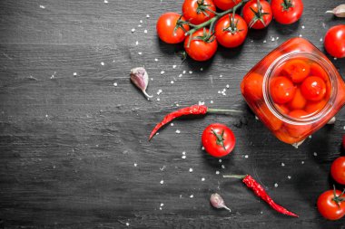 Turşusu domates sarımsak ve otlar ile. Siyah arka plan üzerine.