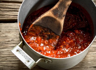 Tencerede domates sosu. Ahşap bir arka plan üzerinde.