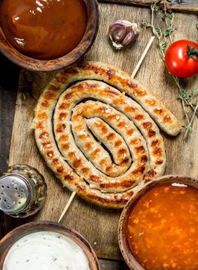 Izgara sosis ve sos. Ahşap bir arka plan üzerinde.