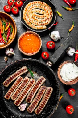 Sarımsak, otlar ve sıcak biber ile kızarmış sosis. Siyah arka plan üzerine.