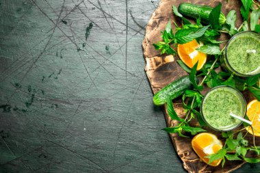 Yeşil sebze, meyve ve nane ile güler yüzlü. Rustik arka plan üzerinde.