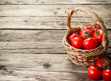 Olgun domates bir sepet içinde. Ahşap bir arka plan üzerinde.