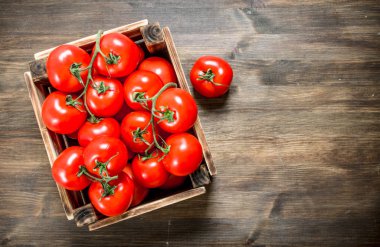 Bir kutu içinde taze domates. Ahşap bir masaya.